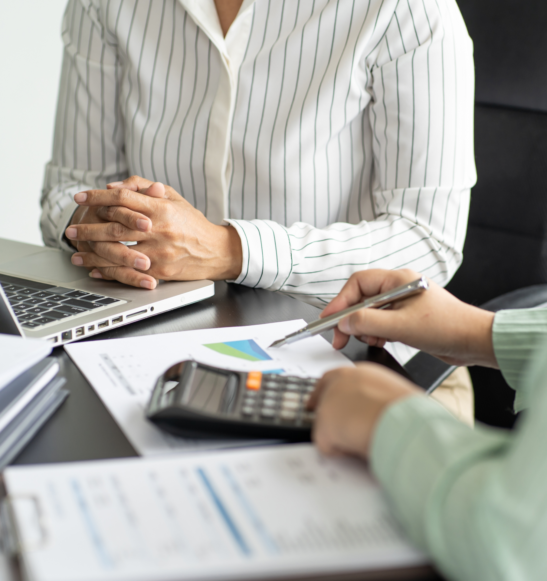 A woman is sitting at a desk with a laptop and a calculator.