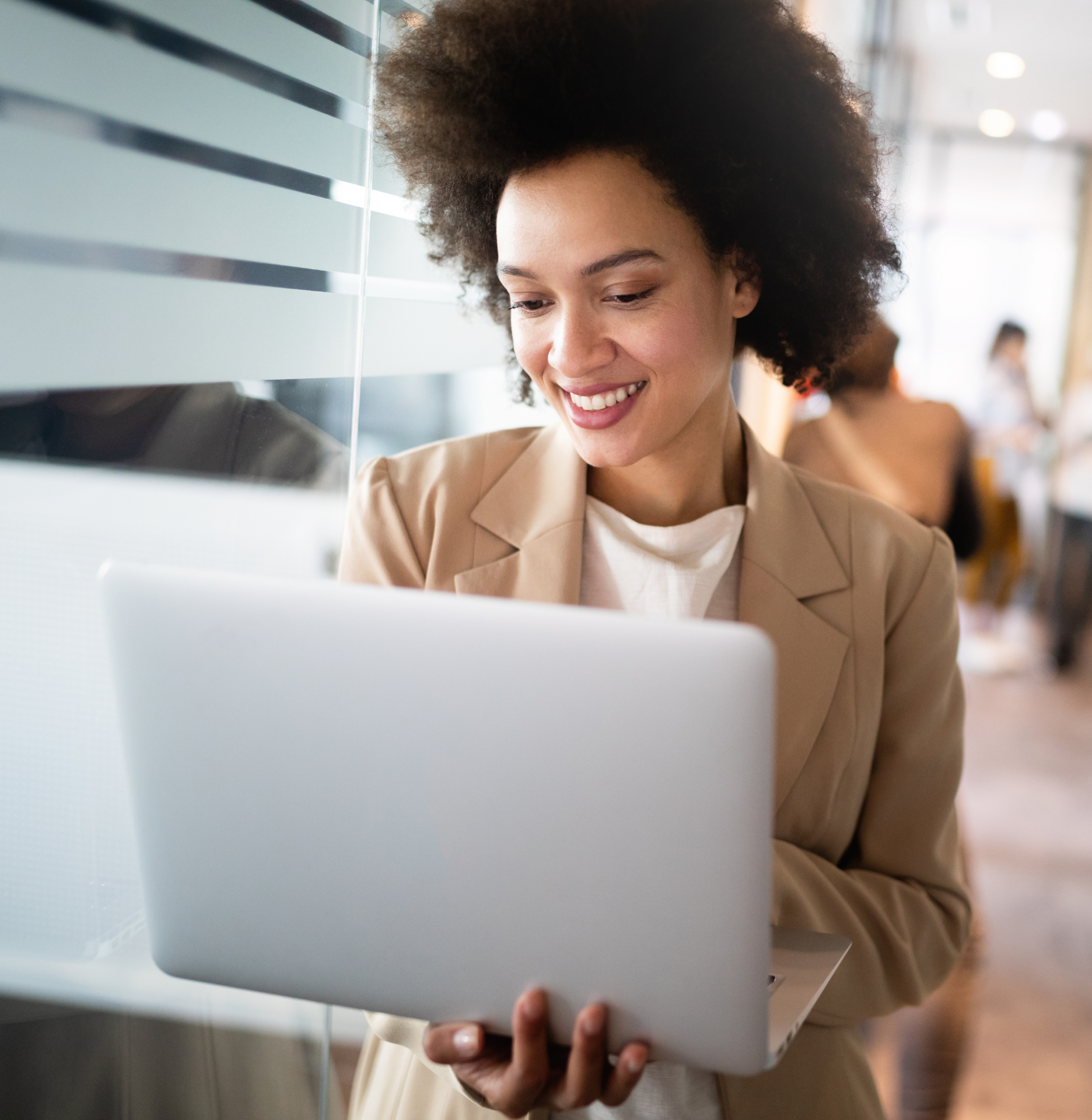 A woman is holding a laptop in her hands and smiling.