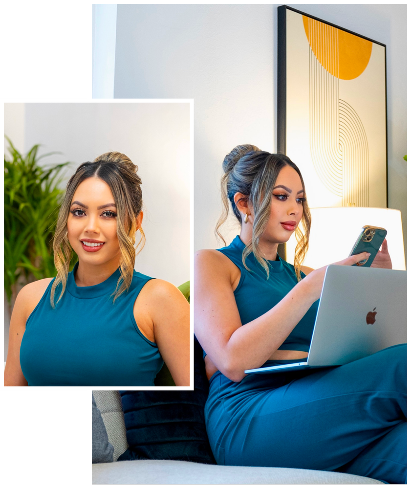 A woman in a blue dress is sitting on a couch using a laptop and a cell phone.