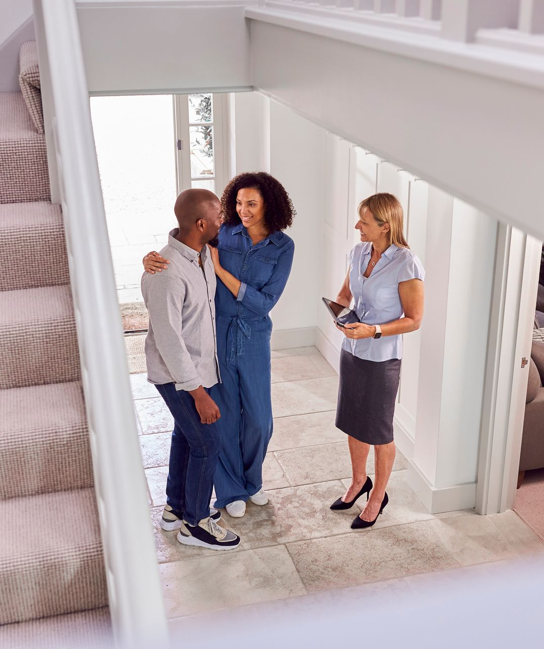 A man and two women are standing in a hallway talking to each other.