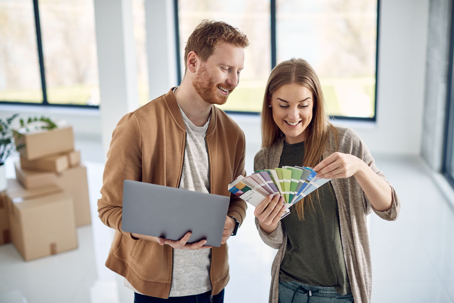 A man and a woman are looking at a color palette and a laptop.