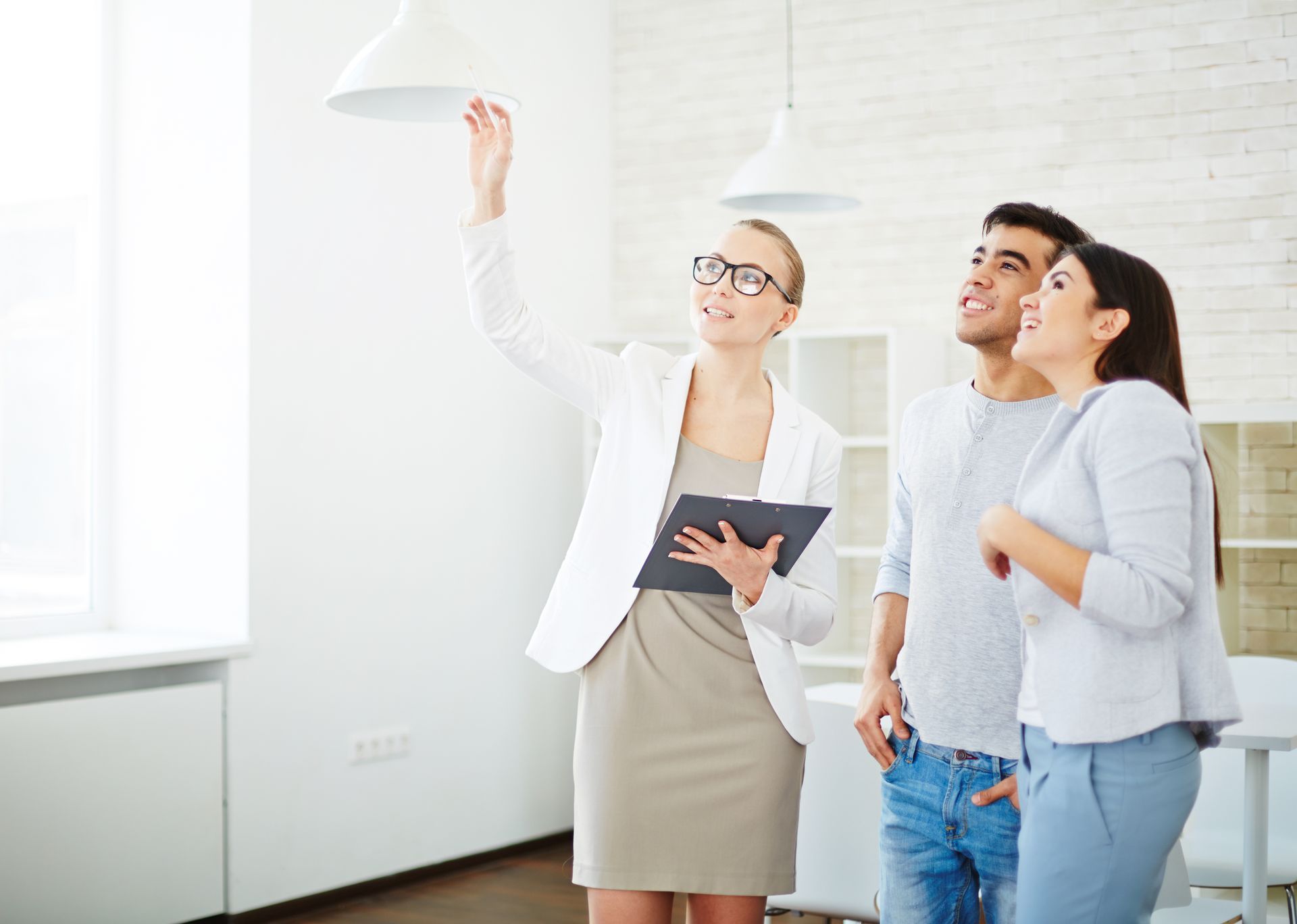 A man and two women are looking up at something while a woman holds a clipboard
