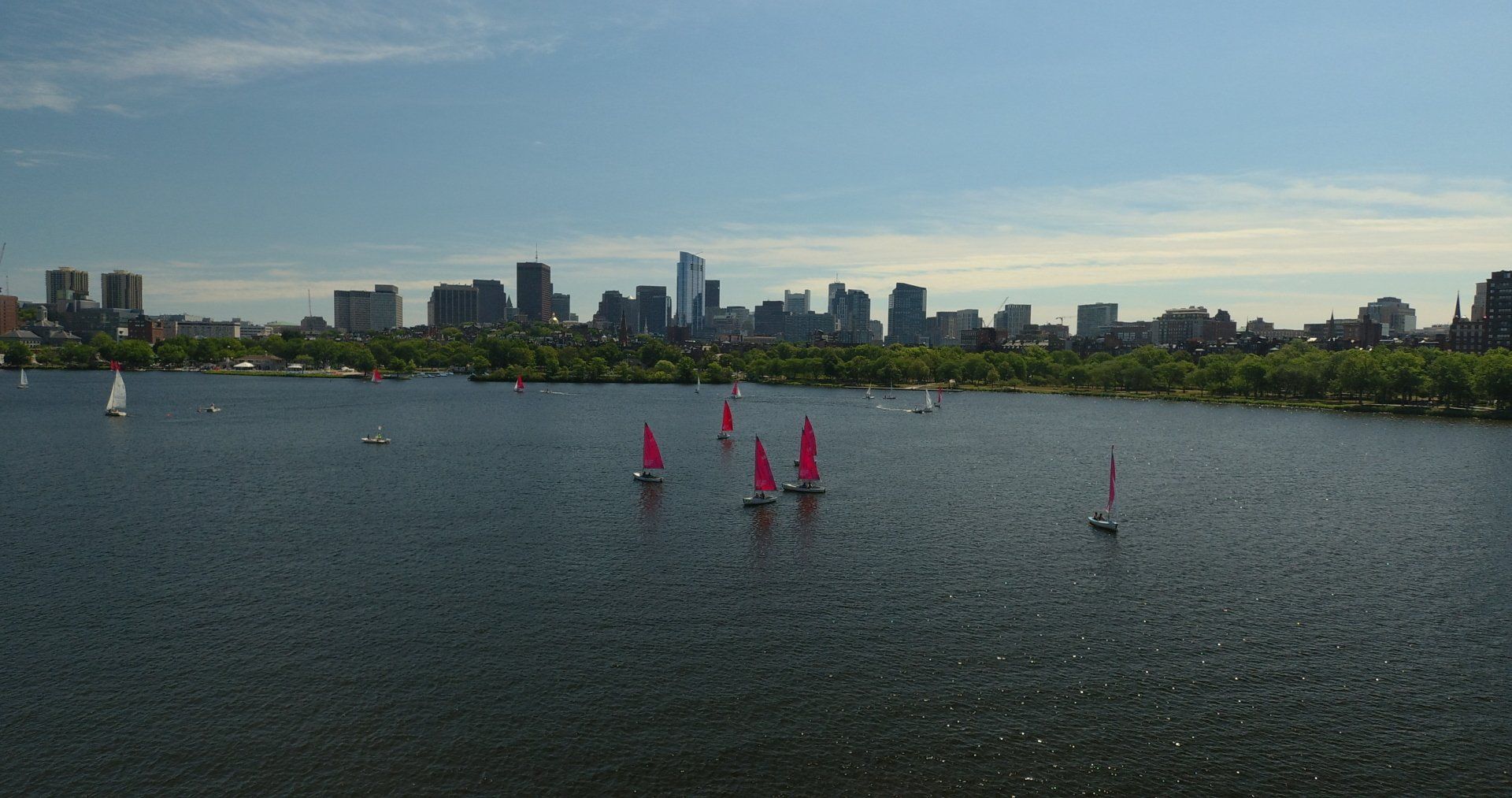 Sailing boats in Boston Charles River with urban city skyline skyscrapers