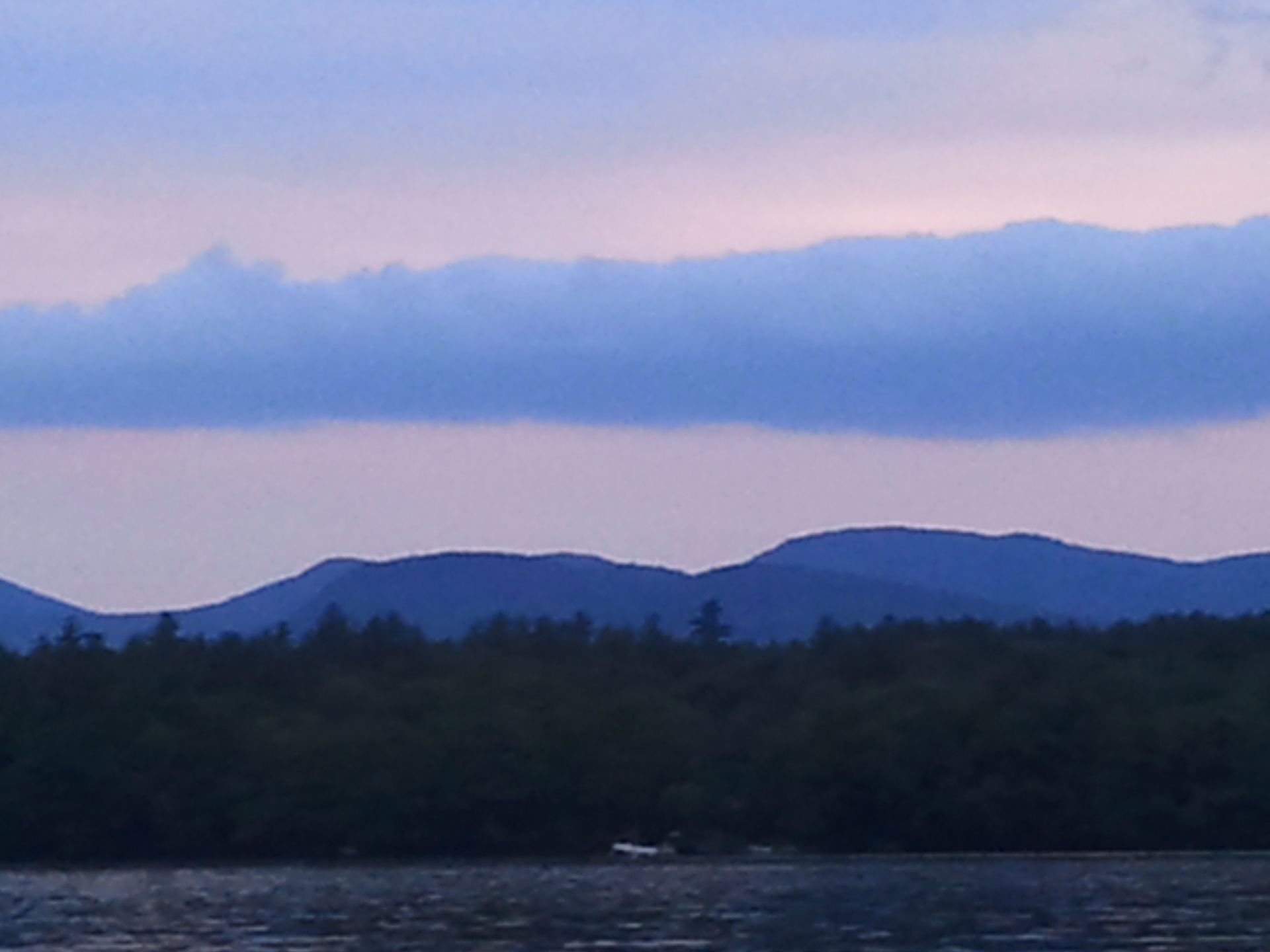 A lake with mountains in the background at sunset