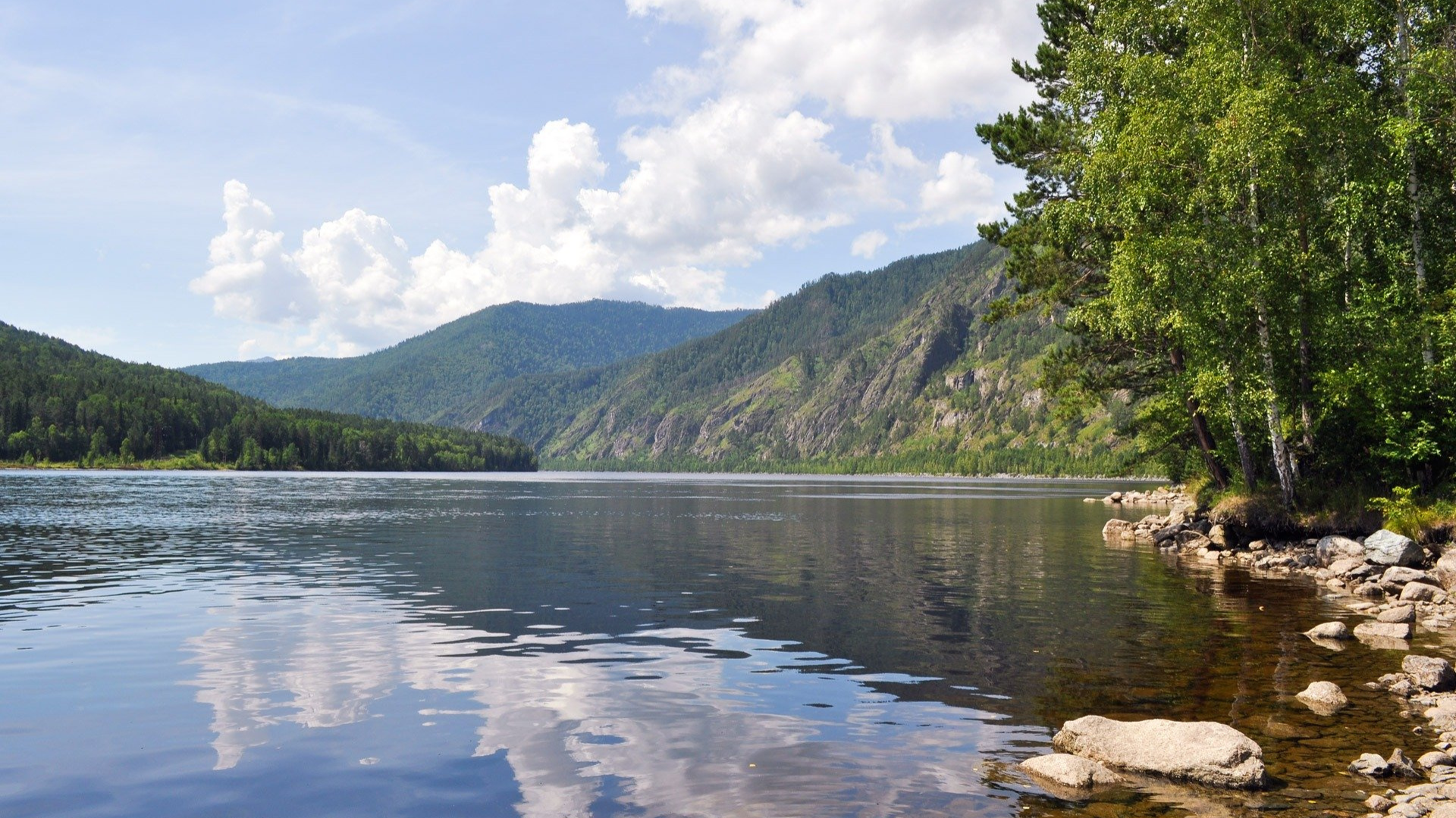 A lake with trees on the shore and mountains in the background