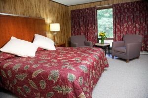 A hotel room with a king size bed and two chairs