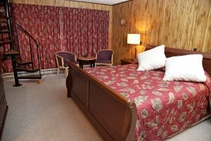 A hotel room with a bed and chairs and a spiral staircase