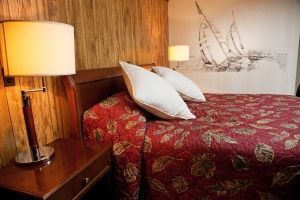 A hotel room with a bed , nightstand , lamp and painting on the wall.