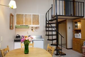 A kitchen with a spiral staircase and a table with a vase of flowers on it.