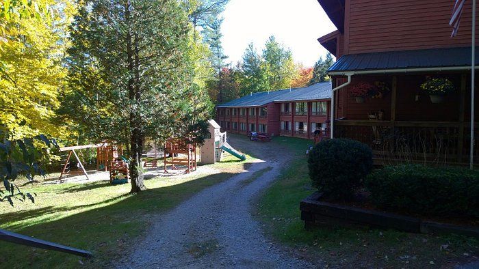 A dirt road leading to a house with a playground in the background.