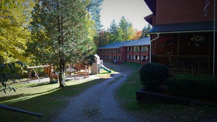 A dirt road leading to a house with a playground in the background.