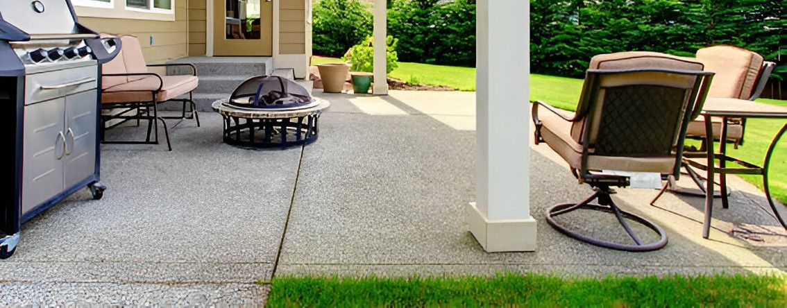 A patio with wicker furniture and a lawn in the background