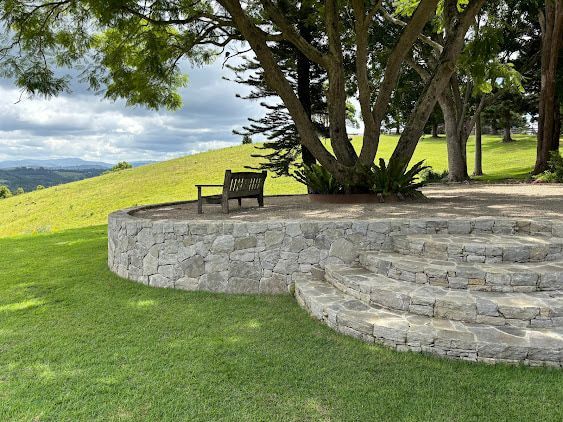 A Stone Wall With Steps Leading Up to a Bench Under a Tree — Tim Williams Landscapes in Wollongbar, NSW