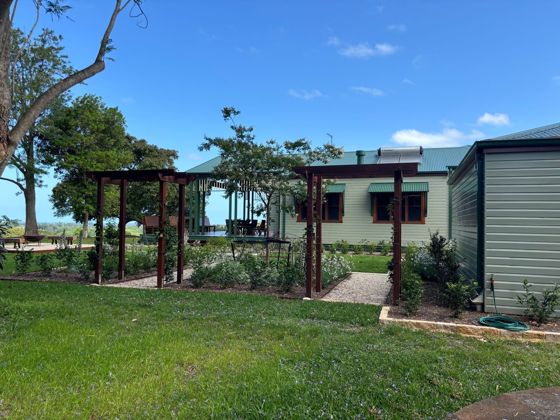 A lawn with a houe in the background and garden with plants and arches — Tim Williams Landscapes in Lennox Head, NSW