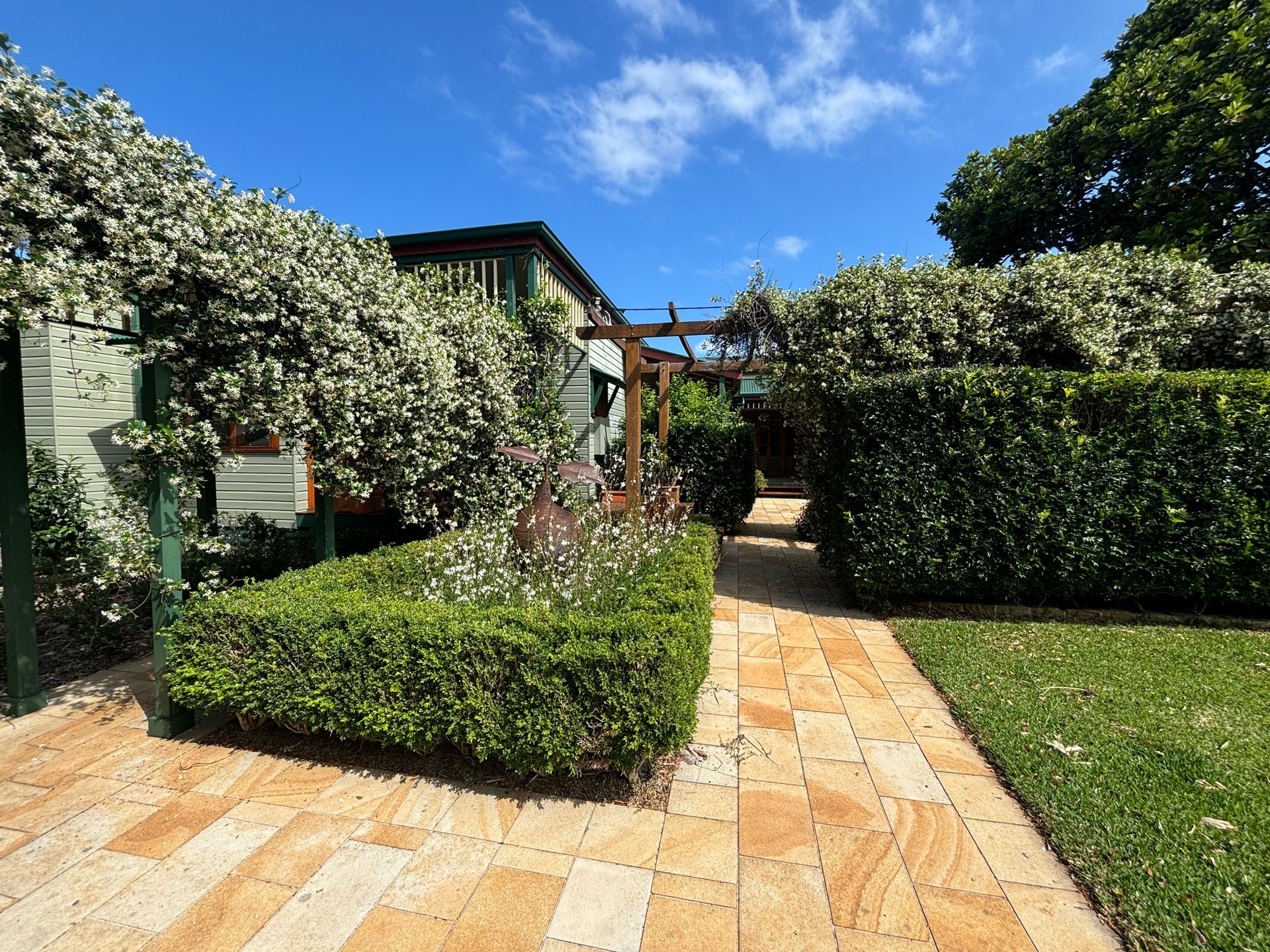 A Backyard With a Lush Green Lawn and light cream tiles — Tim Williams Landscapes in Byron, NSW
