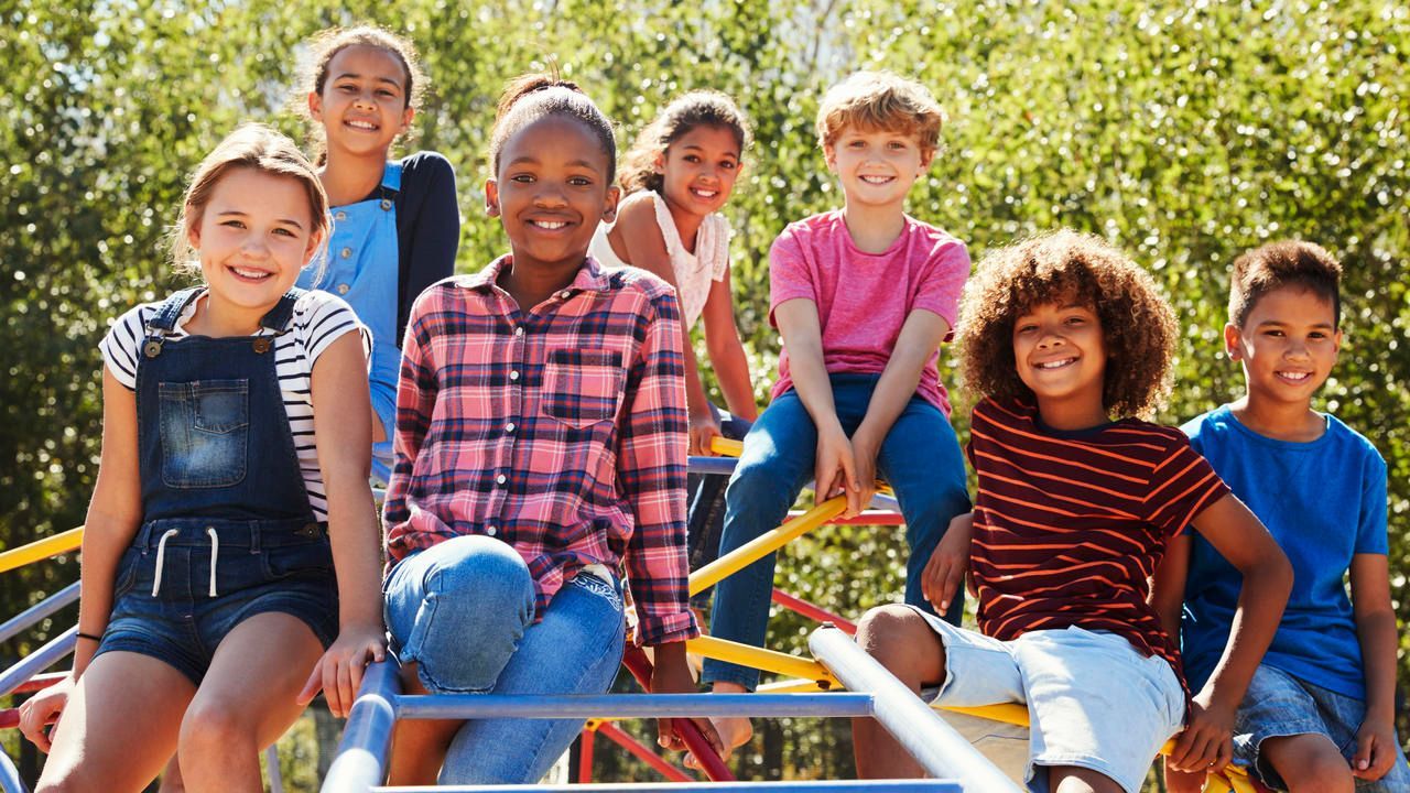 A group of children are sitting on a slide at a playground.