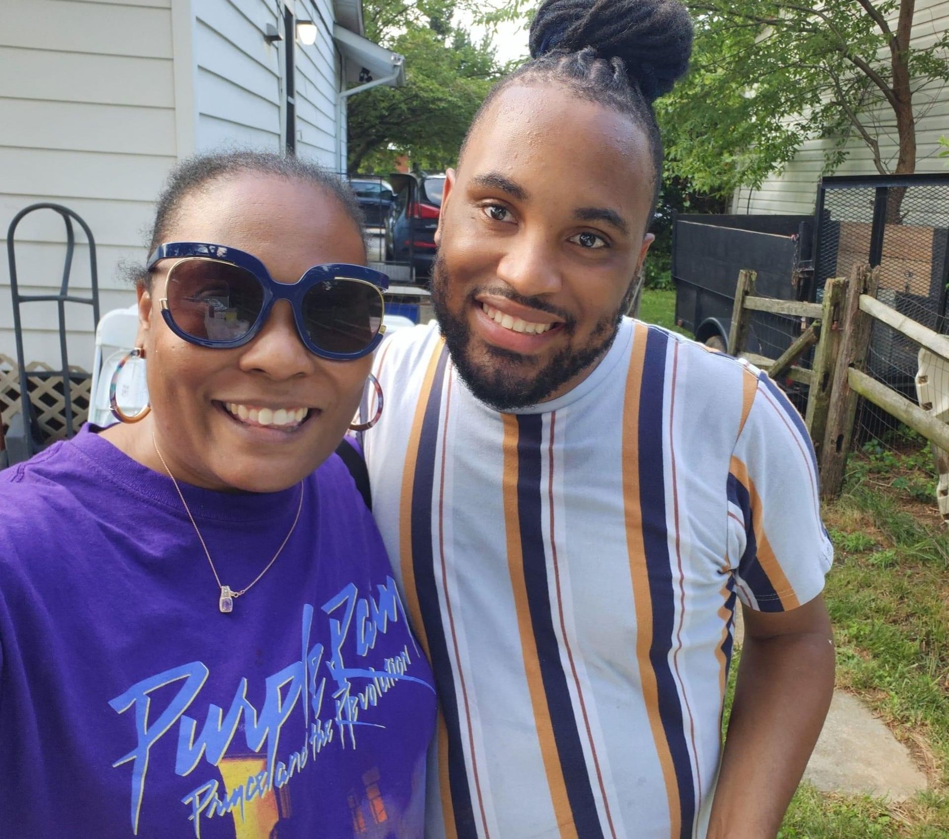 A man and a woman are posing for a picture and the woman is wearing a purple shirt that says purple rain