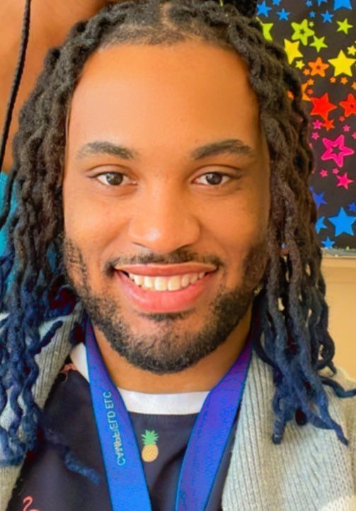 A man with dreadlocks and a medal around his neck