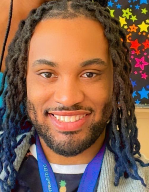 A man with dreadlocks and a medal around his neck