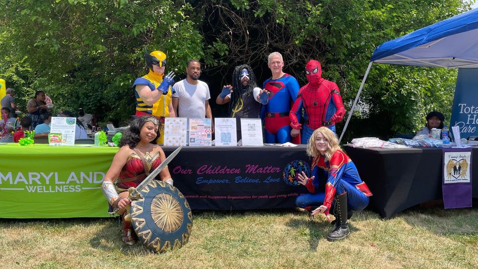 A group of people dressed in superhero costumes are standing around a table.