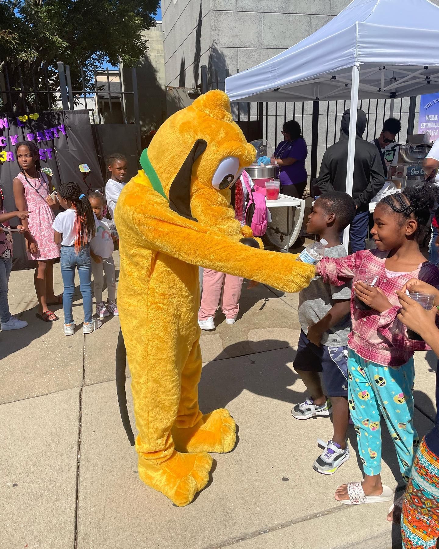A group of children are standing in front of a mickey mouse mascot.