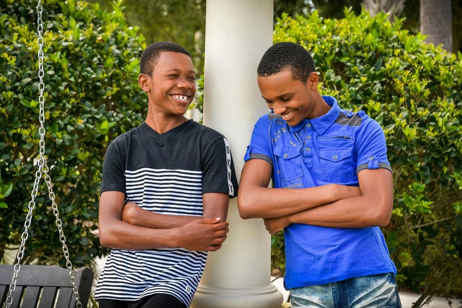 Two young men are standing next to each other and smiling.