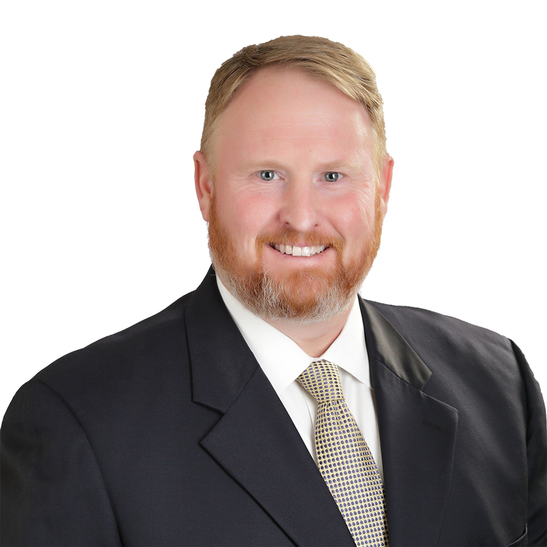 Man with red beard wearing a suit and tie, smiling at the camera.
