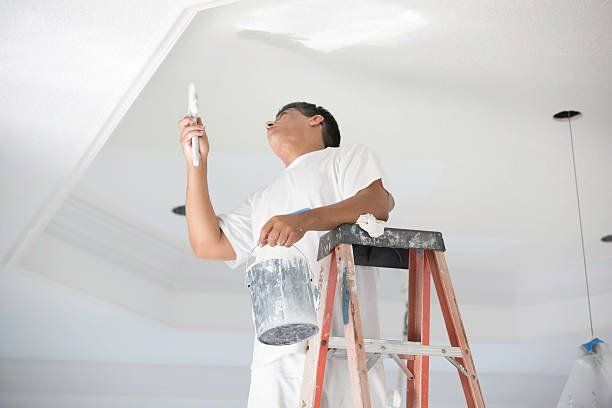 painter on ladder painting ceiling