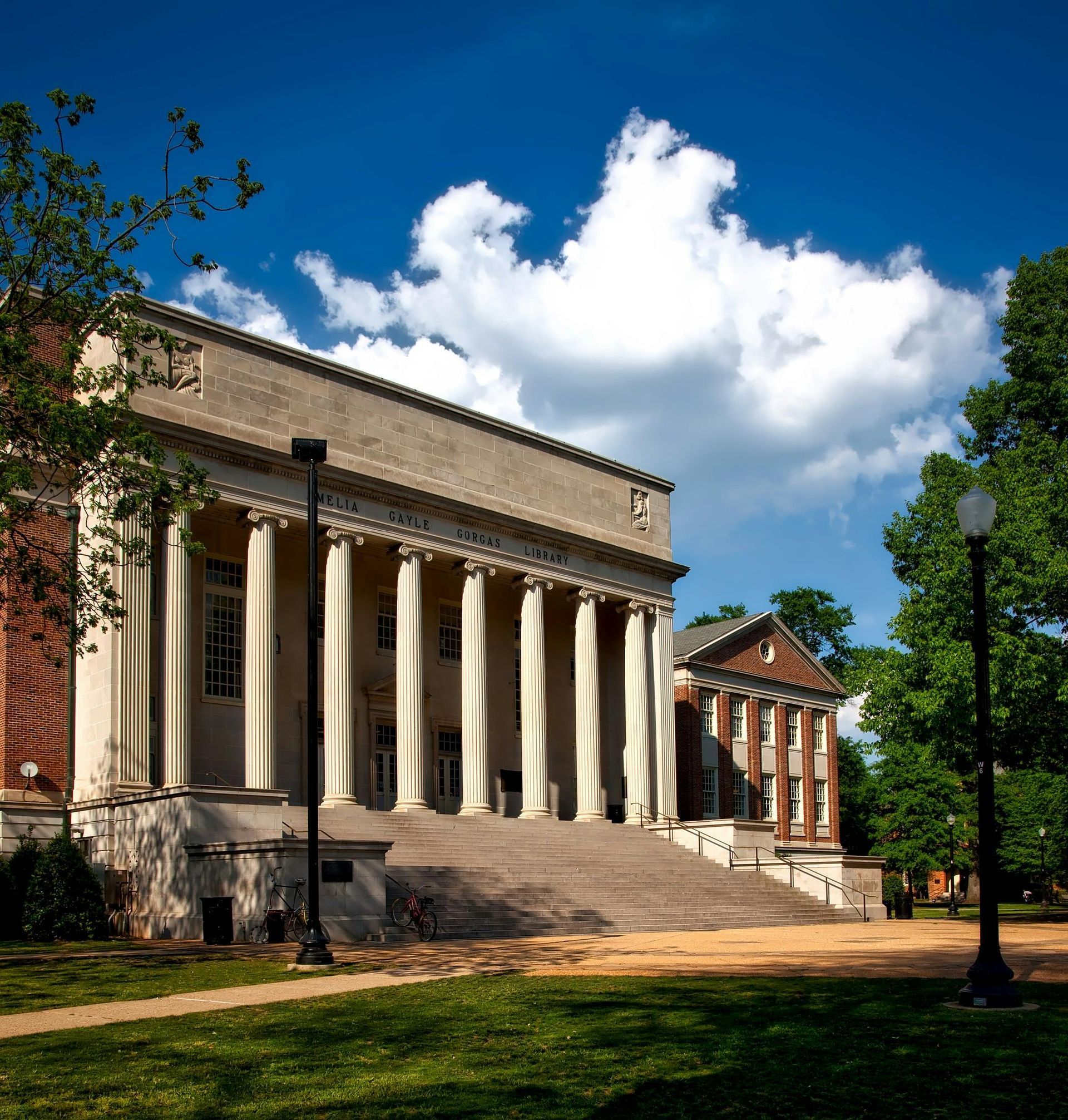 A large building with columns and a brick building in the background