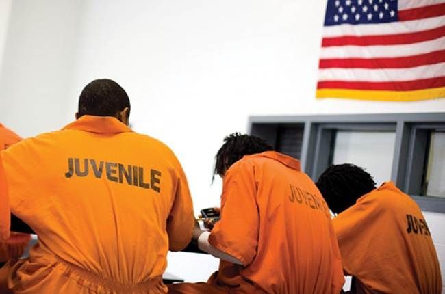 Juvenile offenders in a carceral facility, dressed in orange jumpsuits.