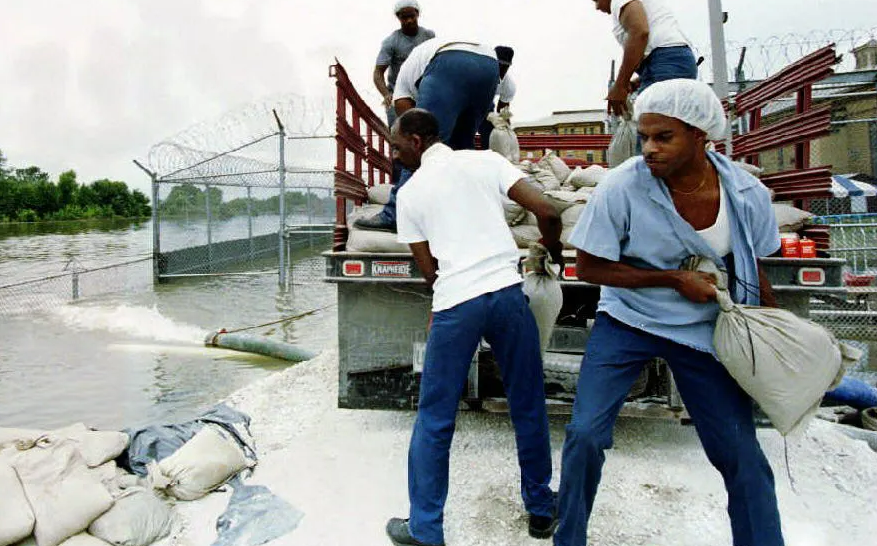 Incarcerated workers sandbagging a flooded prison yard (Eugene Garcia/Getty Images)