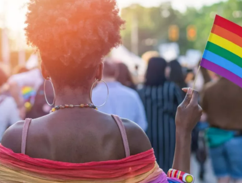 Photo: Black woman participating in a march, holding a Pride flag. (Photo: Innocence Project)