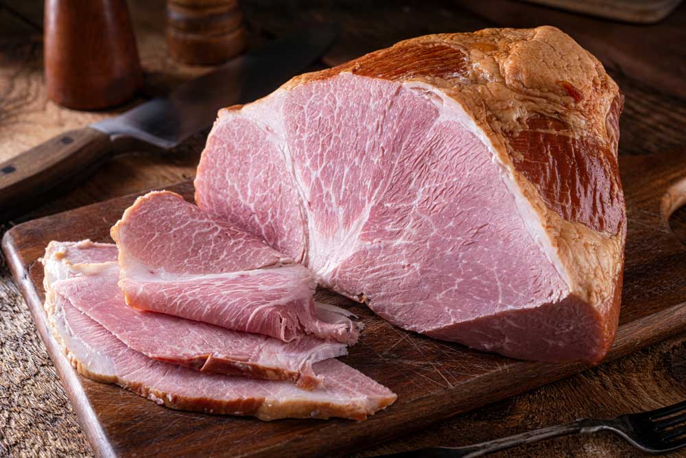A delicious naturally smoked ham on a rustic wood cutting board