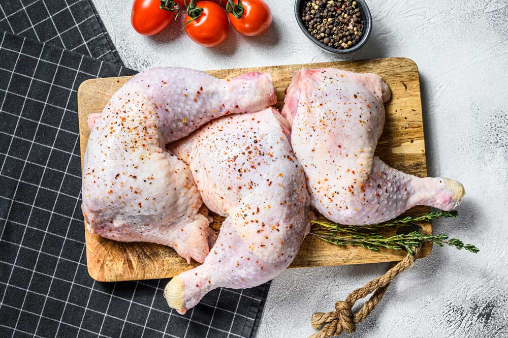 Fresh raw chicken thighs, legs on a cutting board with spices