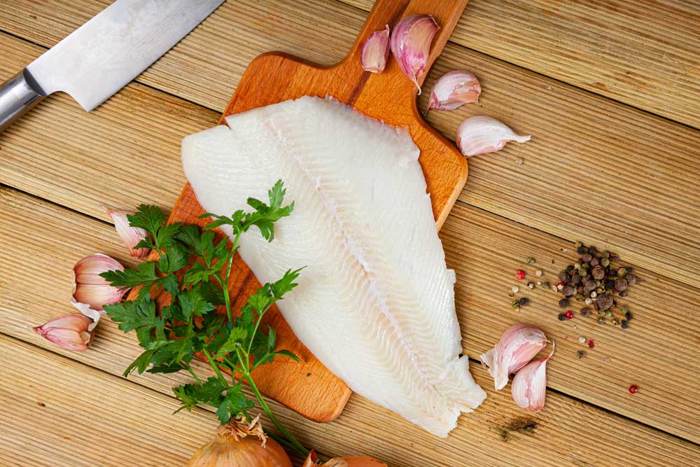 Fresh raw flounder fillet with greens and spices
