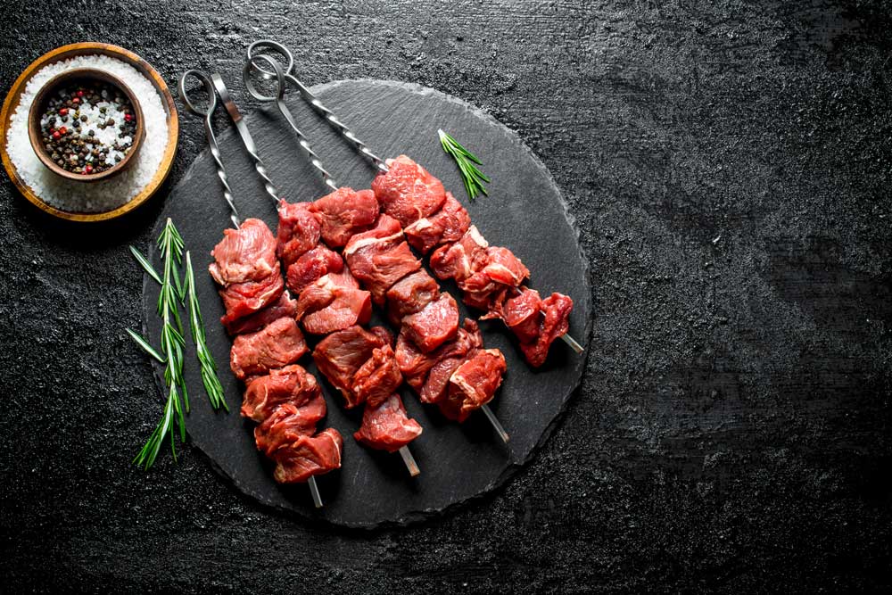 Raw kebab on a stone Board with rosemary and spices