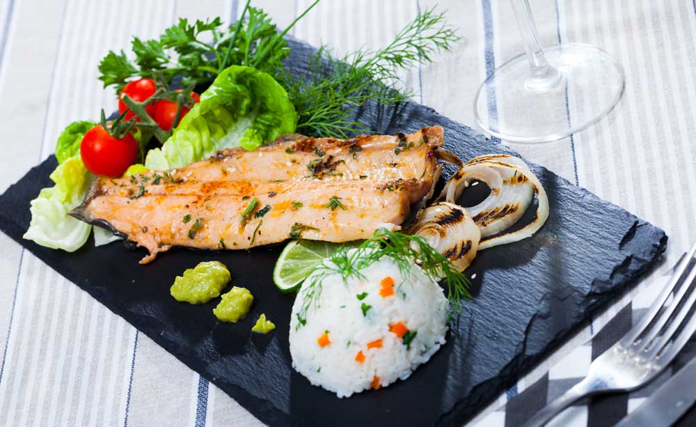 Tasty fried trout fillet with rice, tomatoes and greens