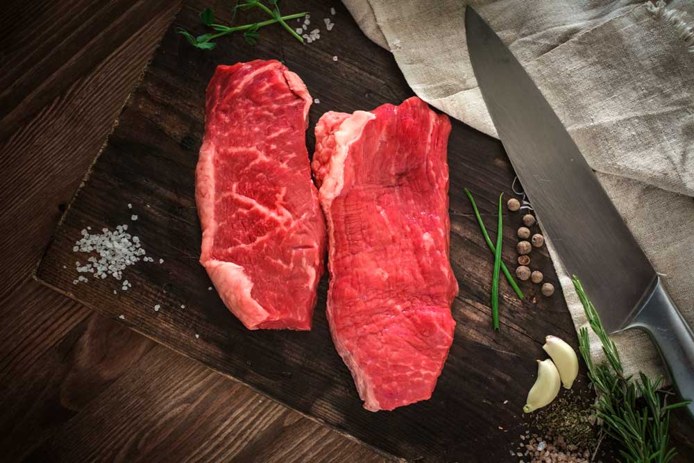 Two raw chuck steak on a wooden Board on a table prepared for the grill