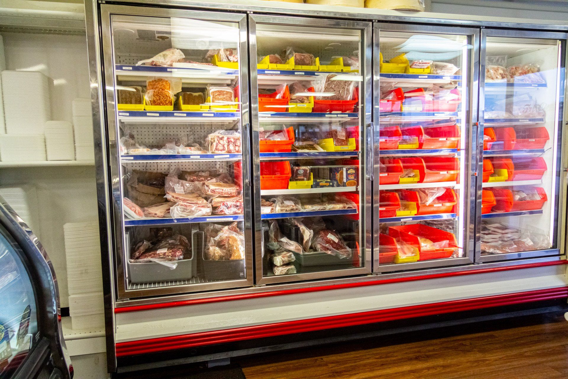 A refrigerator filled with lots of meat in a butcher shop.