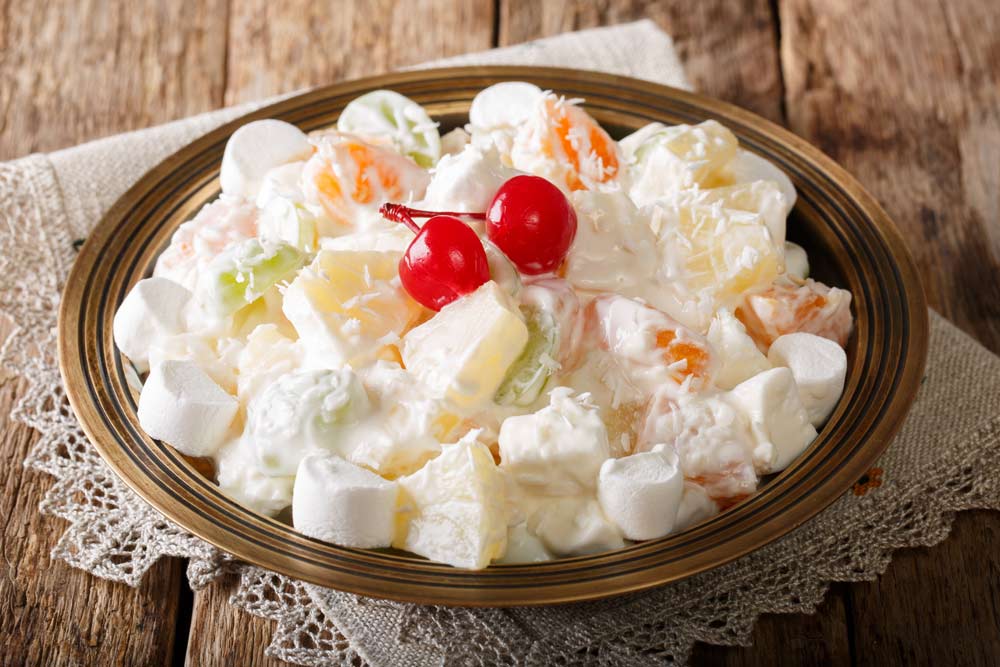 fruit salad from pineapple, oranges, grapes and coconut with marshmallow and vanilla yogurt
