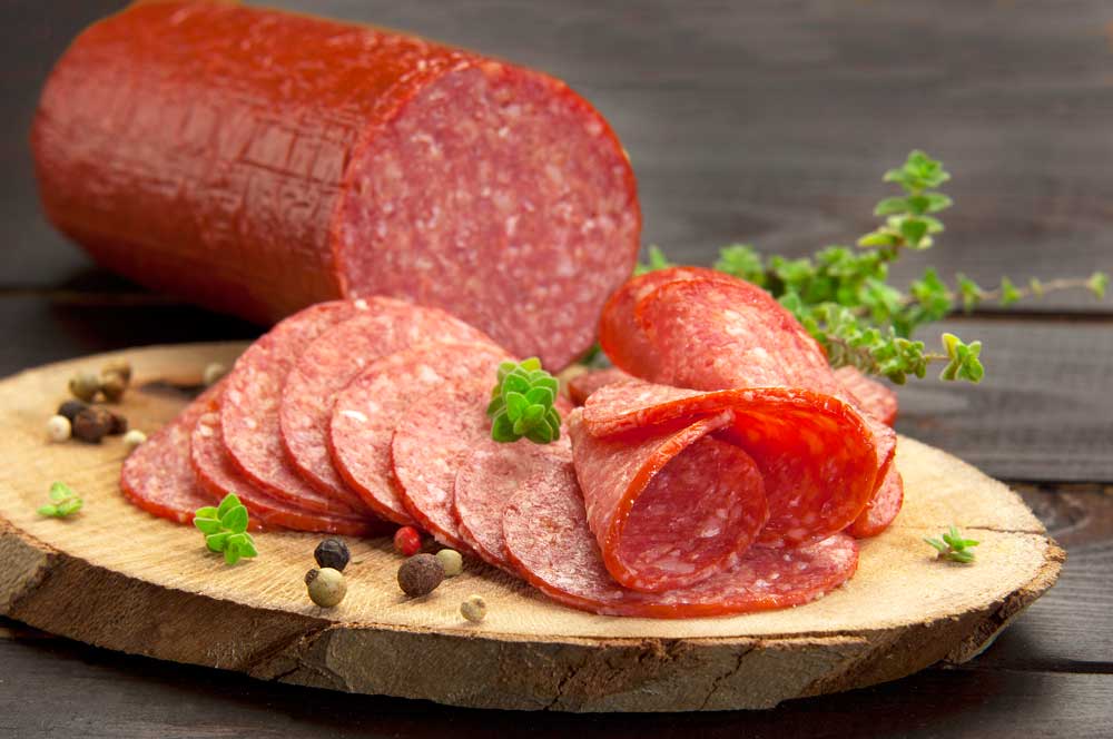 turkey salami served on a slice of wood with thyme and ground pepper