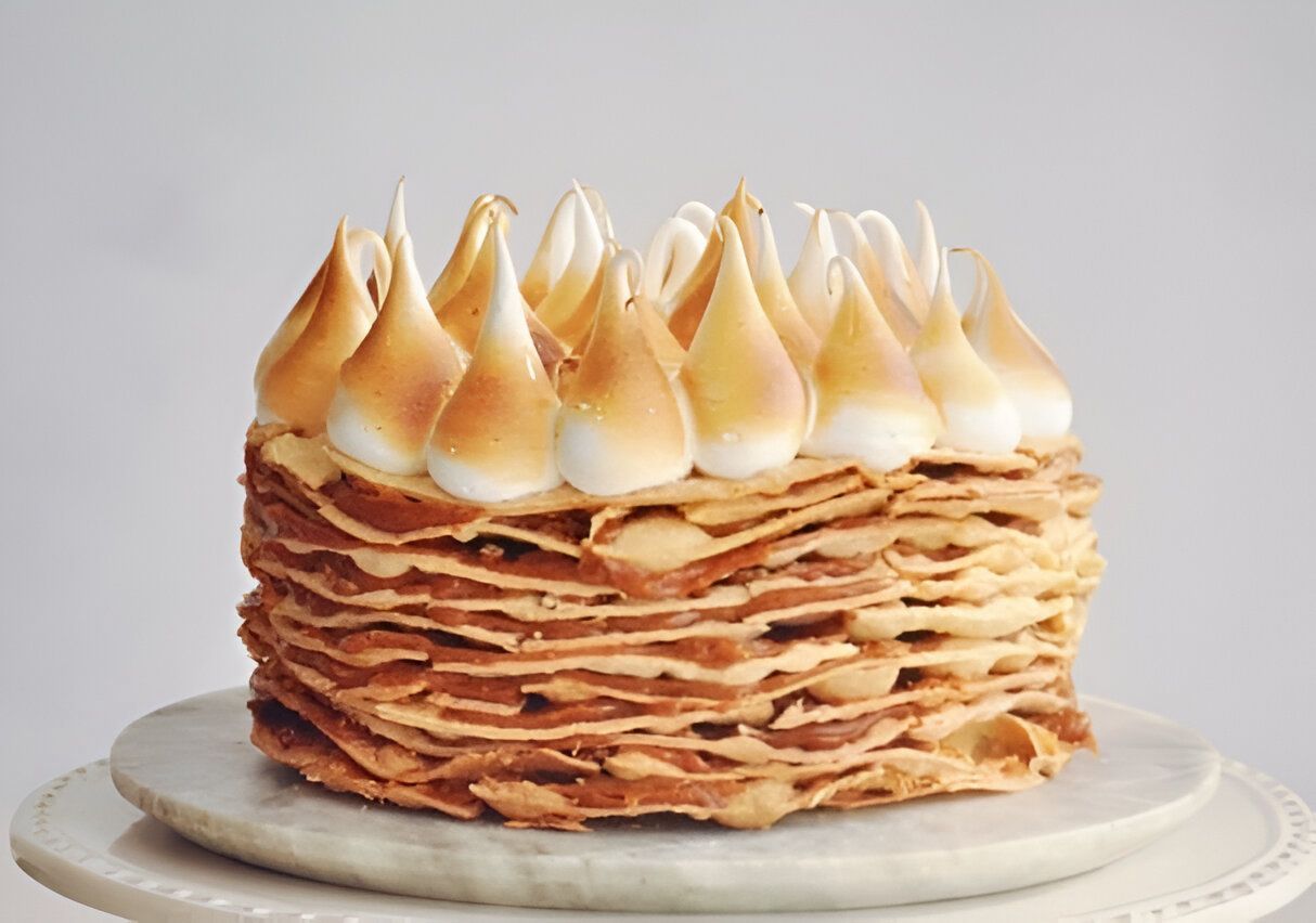 Un pastel con merengue encima está sobre un plato blanco.