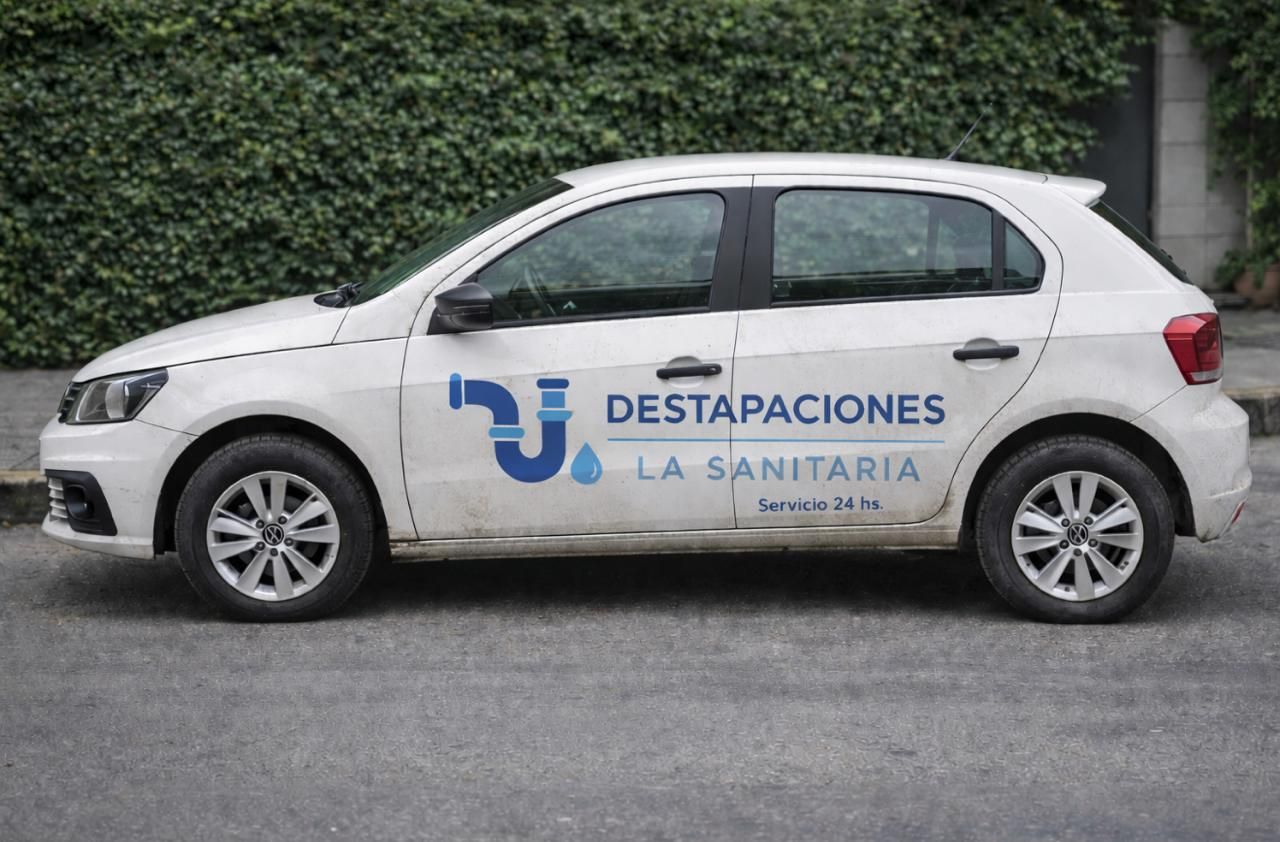 Coche de empresa blanco con el logotipo “Desatascions La Sanitaria” aparcado en una calle.
