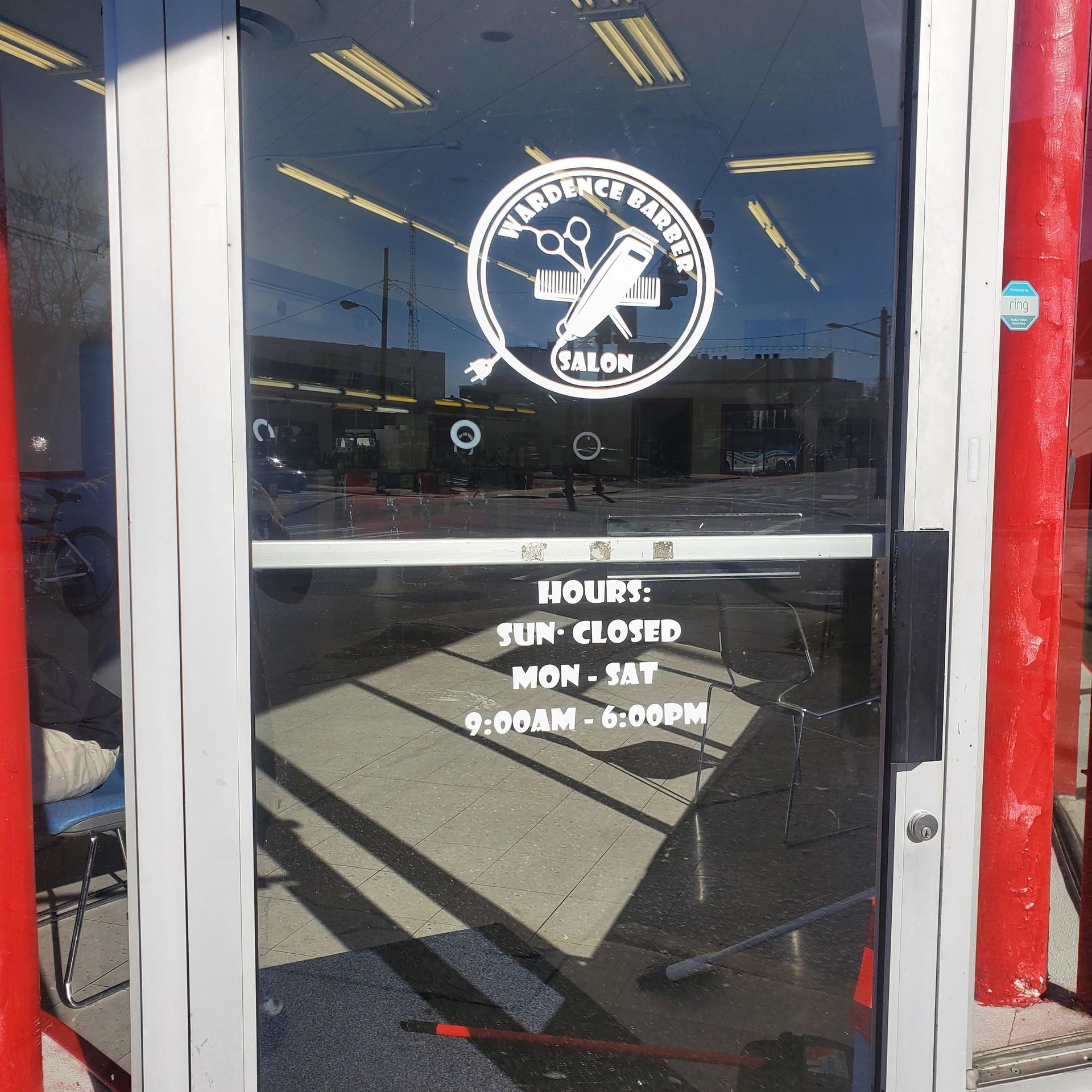 A barber shop has a sign on the door that says hours