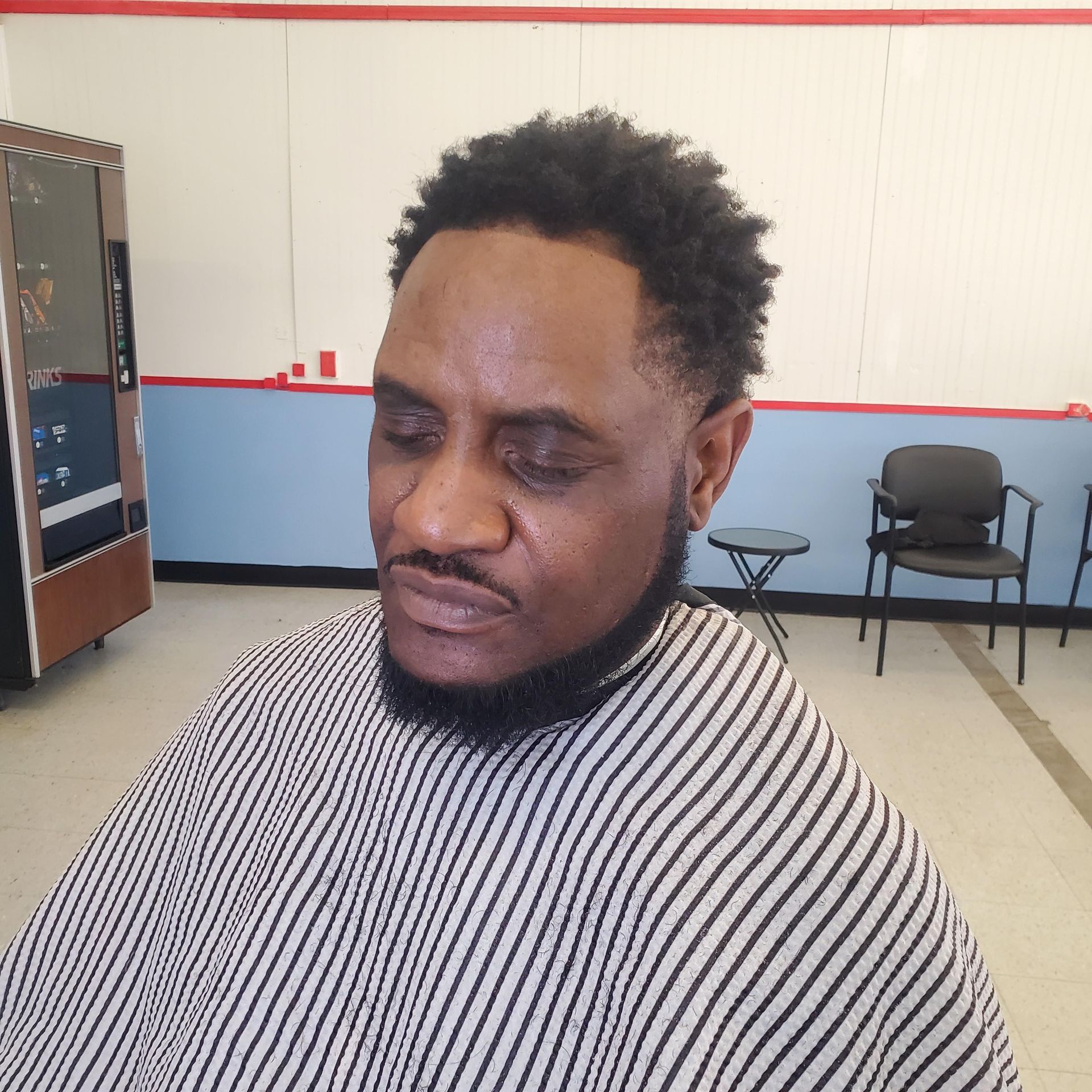 A man with a beard is getting his hair cut at a barber shop