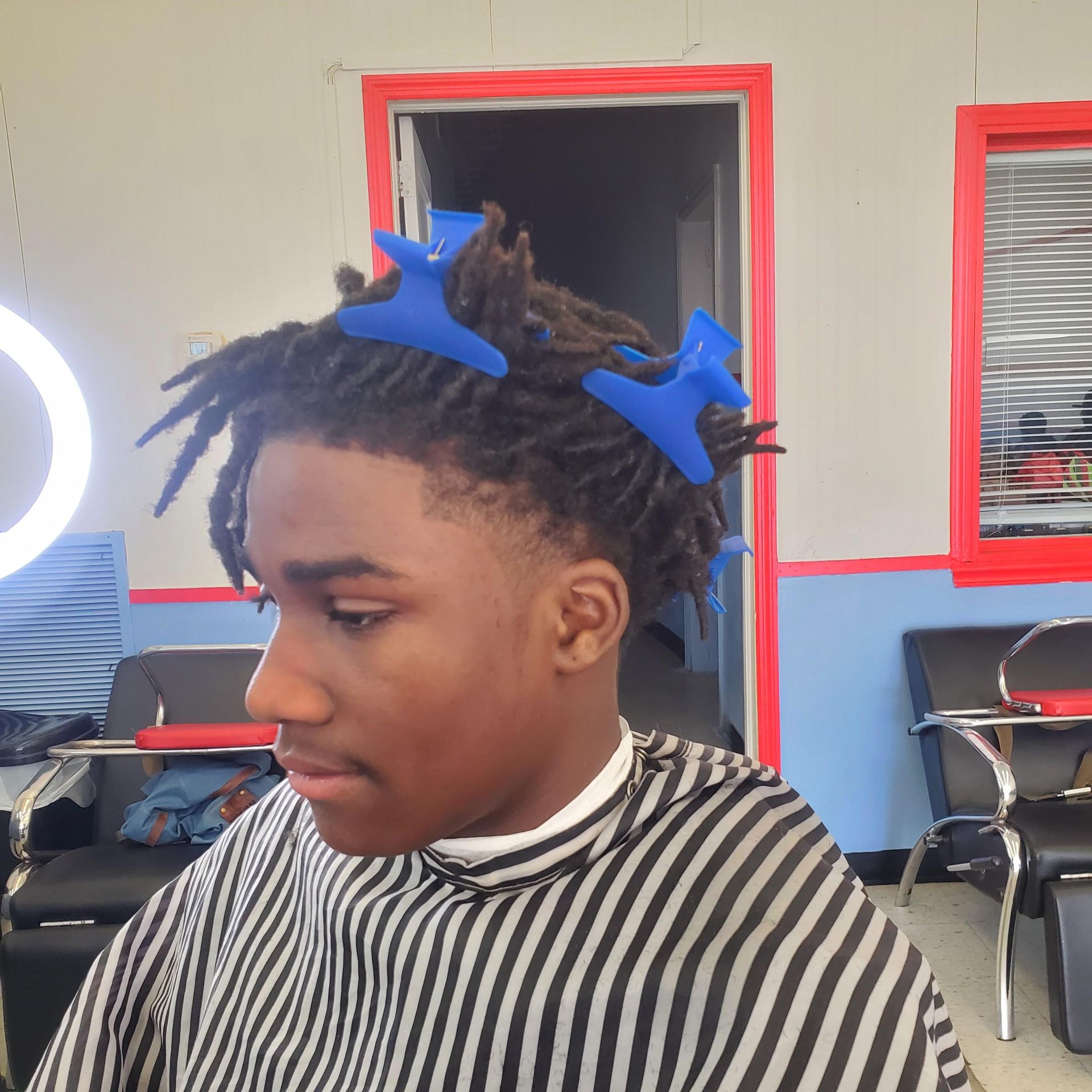 A young man is getting his hair cut at a barber shop.
