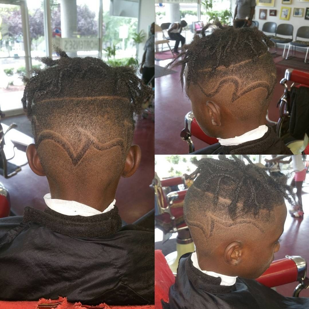 A boy with dreadlocks is getting his hair cut by a barber