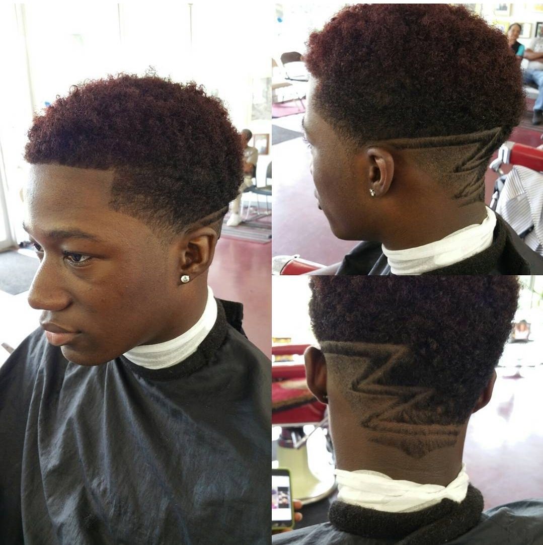 A young man is getting his hair cut at a barber shop