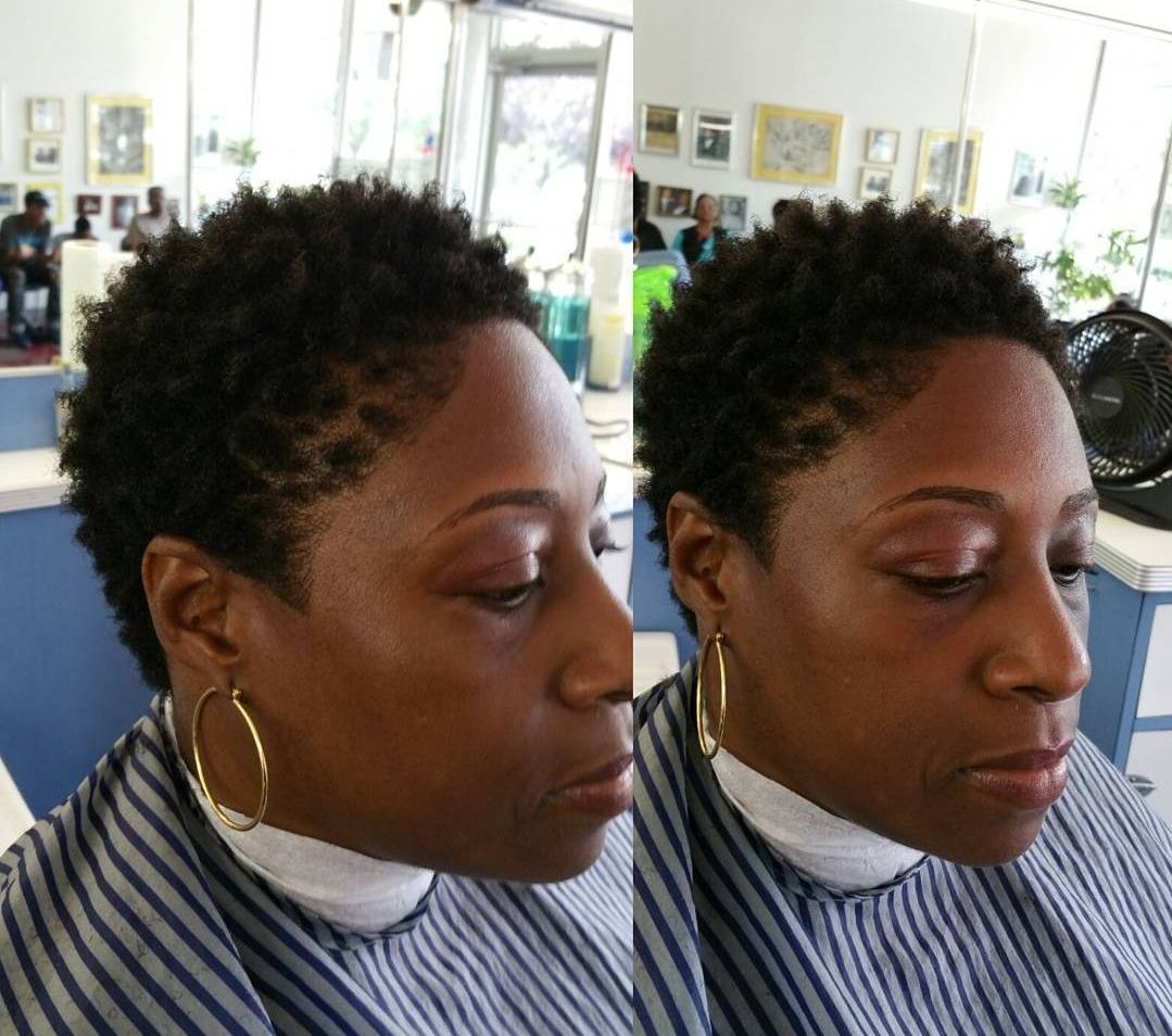 A woman is getting her hair cut in a barber shop