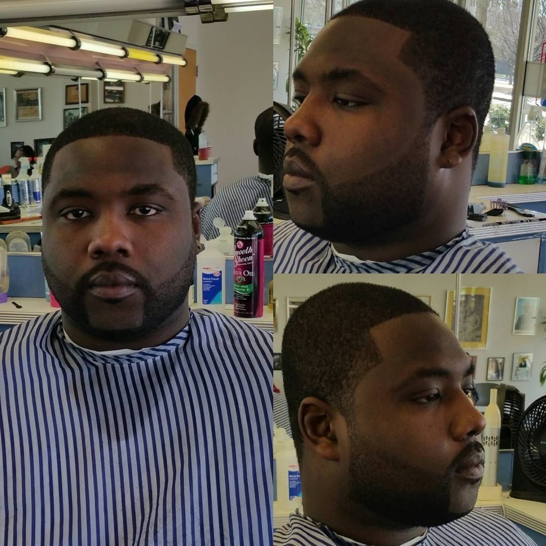 A man with a beard is getting his hair cut in a barber shop